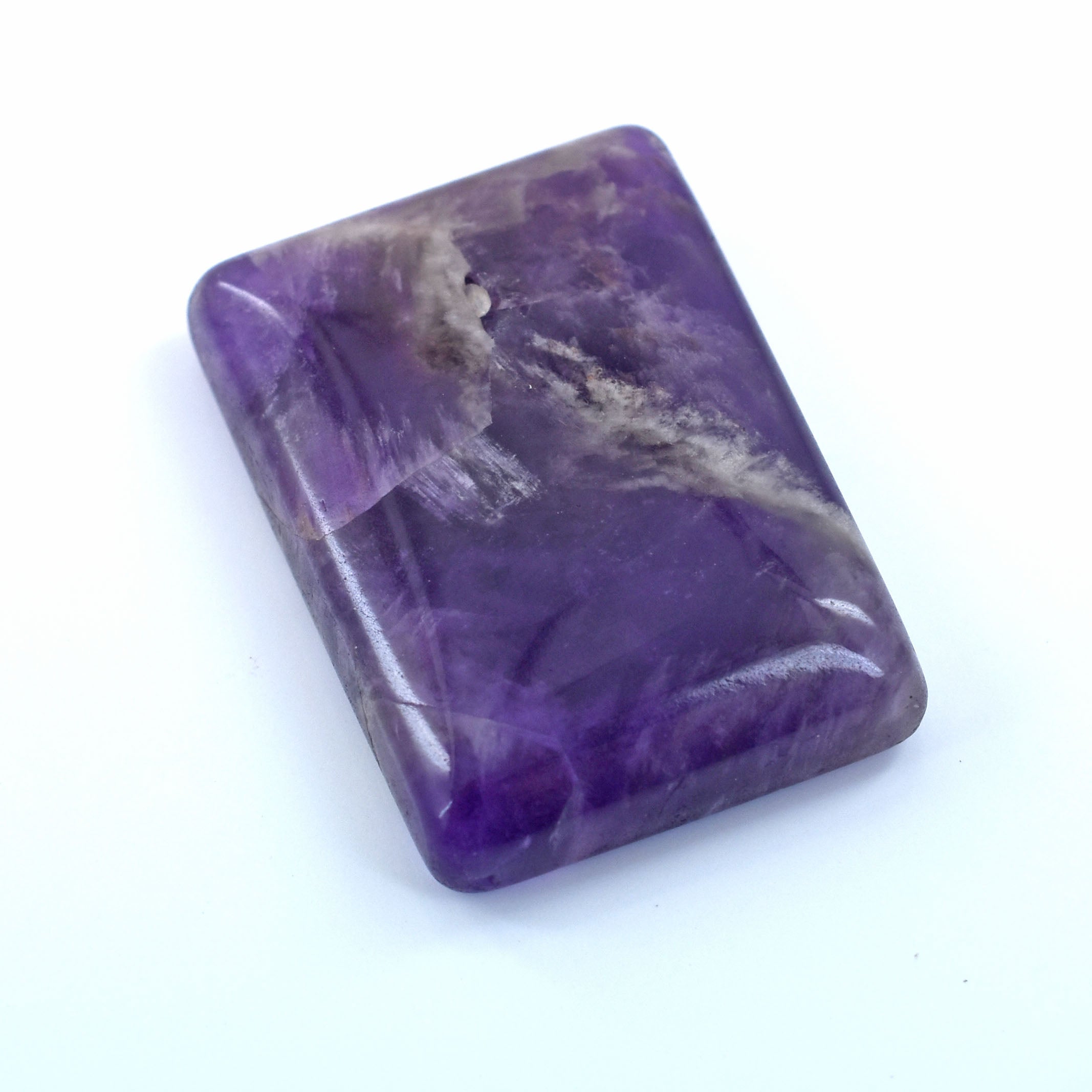 Rectangular purple gemstone or mineral with swirling patterns.