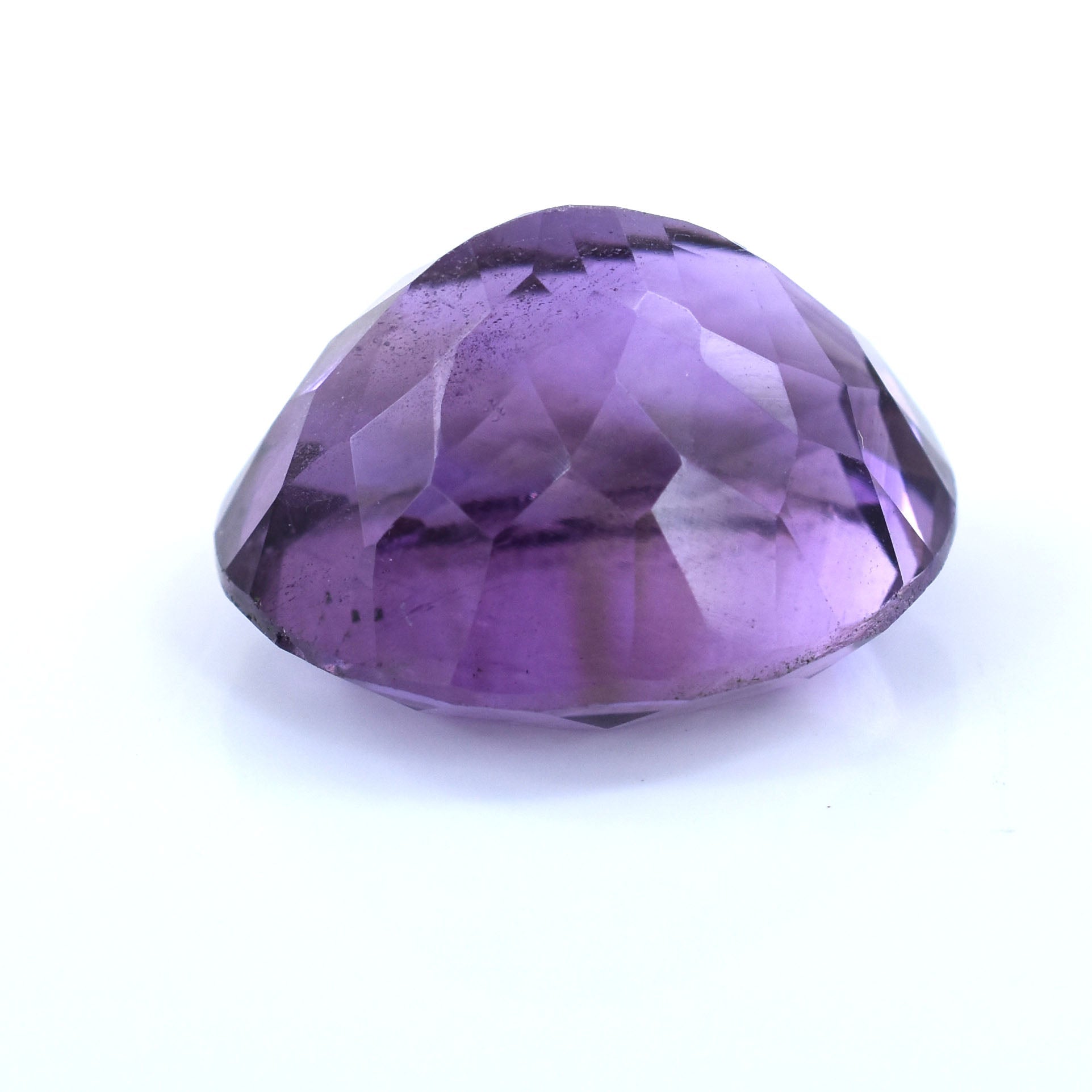 Faceted purple gemstone with a rounded oval shape.