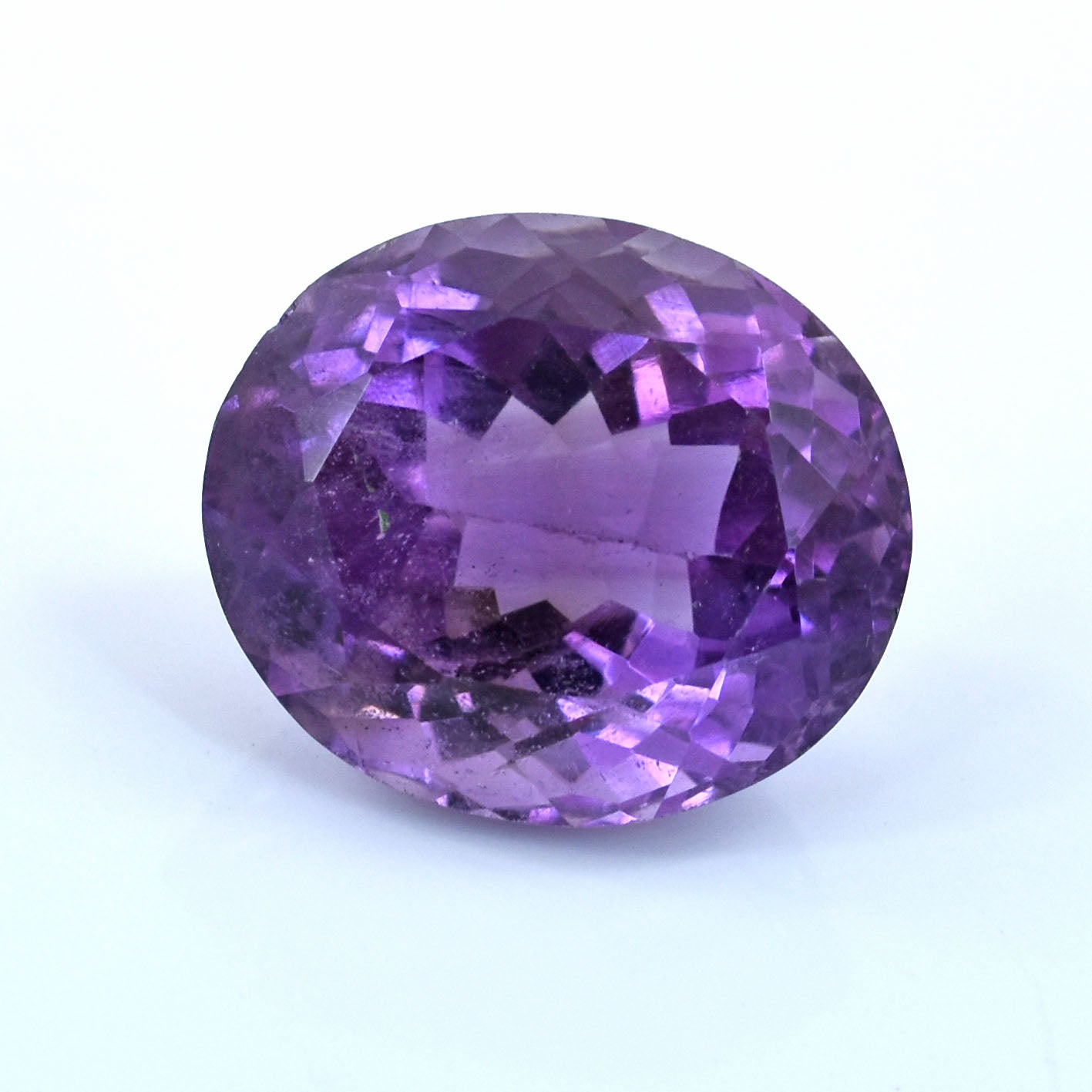 Oval-cut purple gemstone with facets reflecting light.