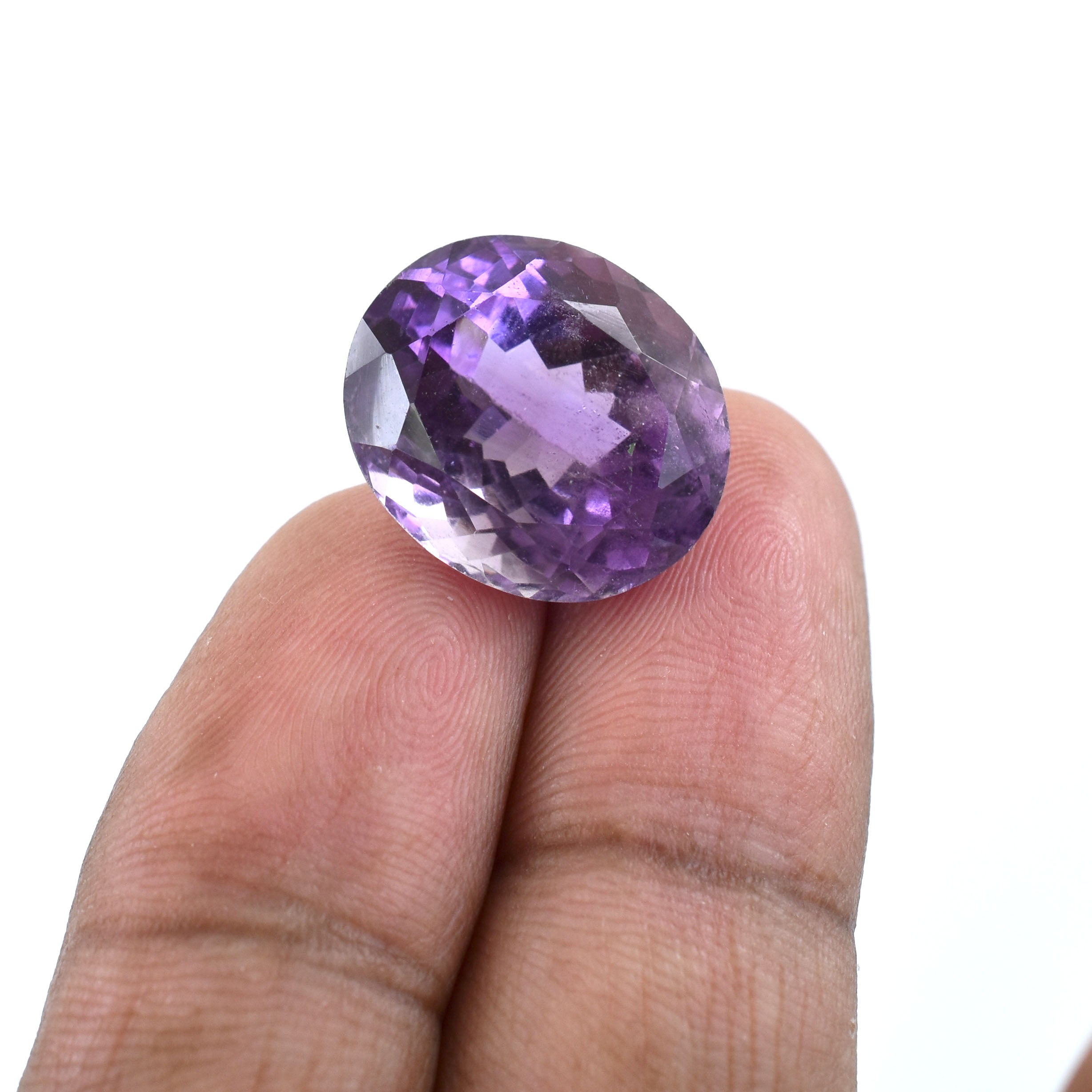 Faceted purple gemstone held between two fingers.