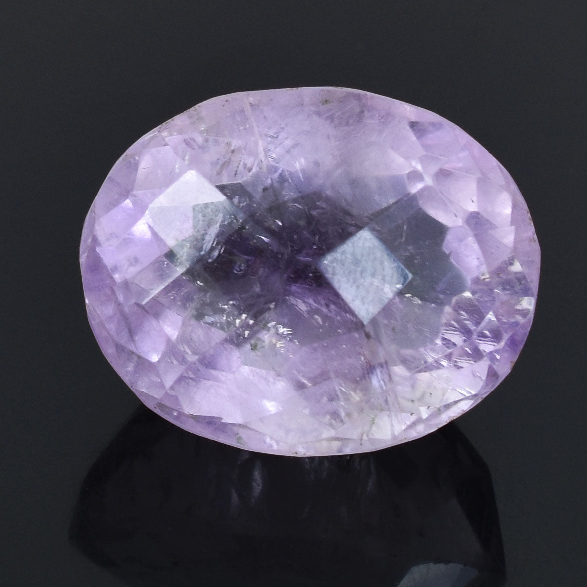 Oval-cut light purple gemstone with facets reflecting light.