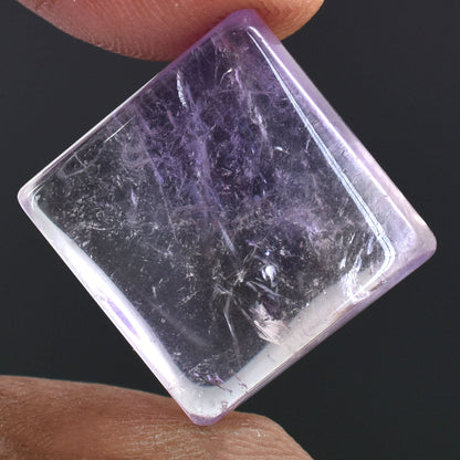 Square-cut gemstone or crystal with a purple hue and internal inclusions.