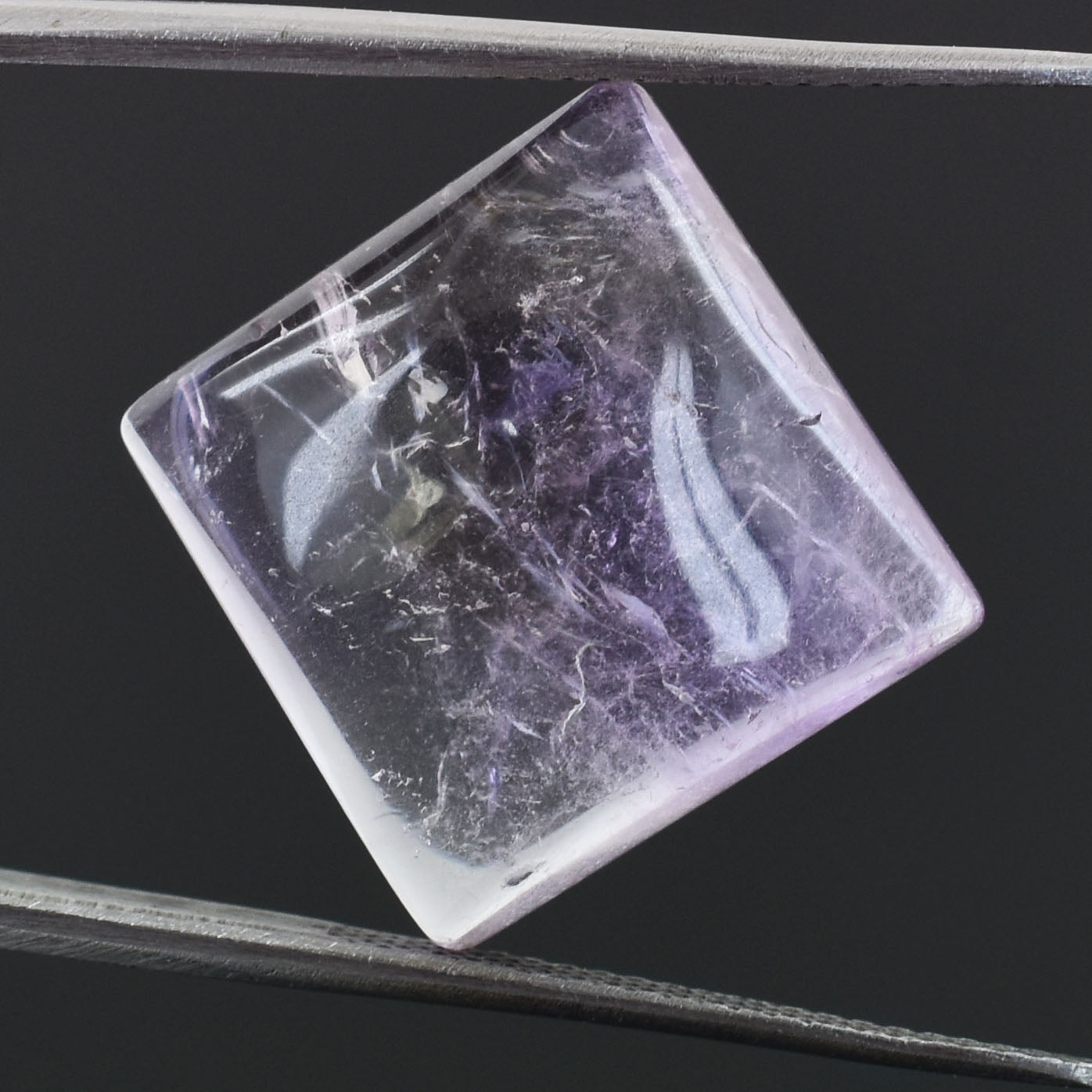 Square-shaped crystal or gemstone with purple and white swirling patterns inside.