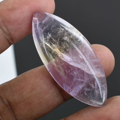 Oval-shaped gemstone or crystal with a pinkish-purple hue and internal inclusions.