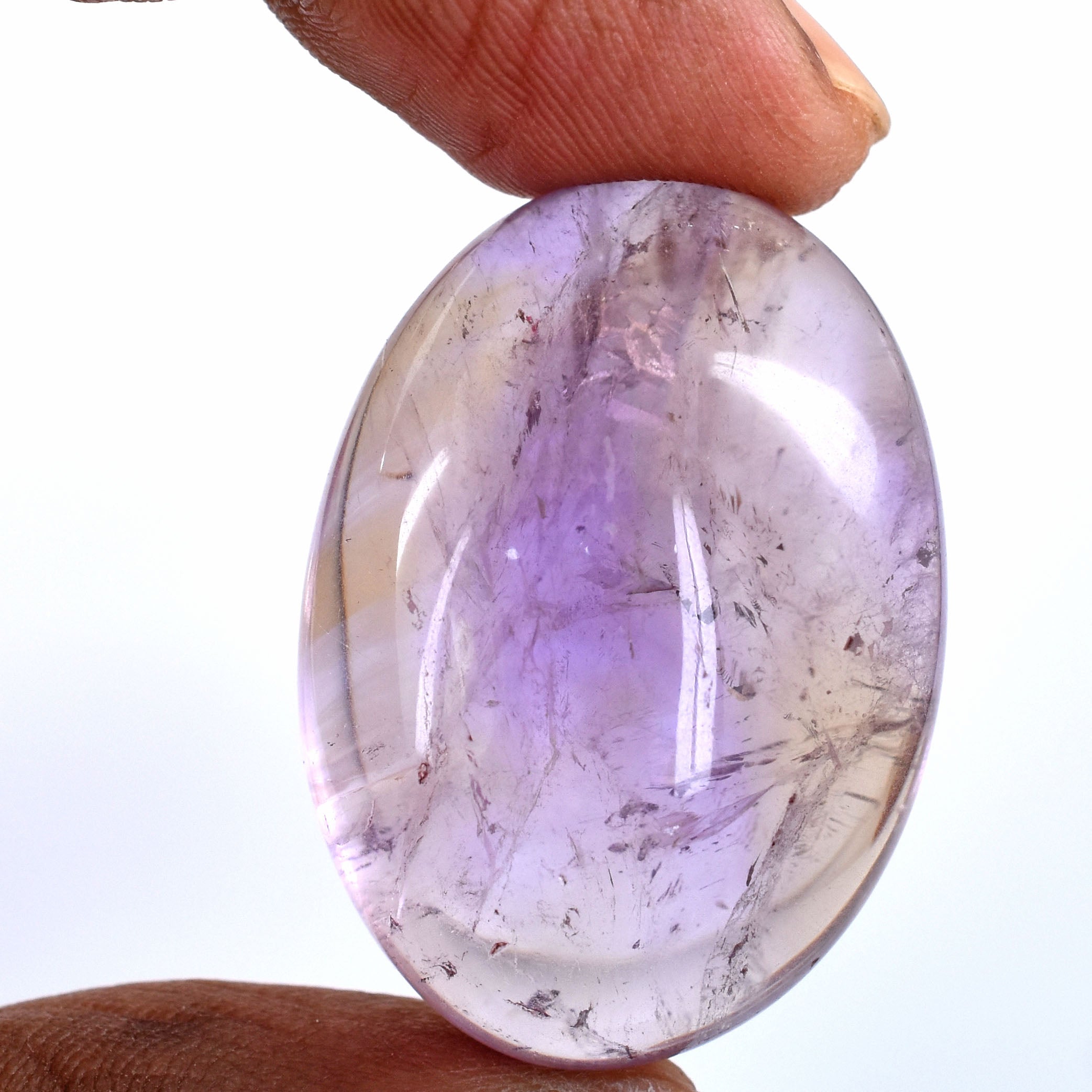 Oval-shaped, translucent purple gemstone held between fingers.