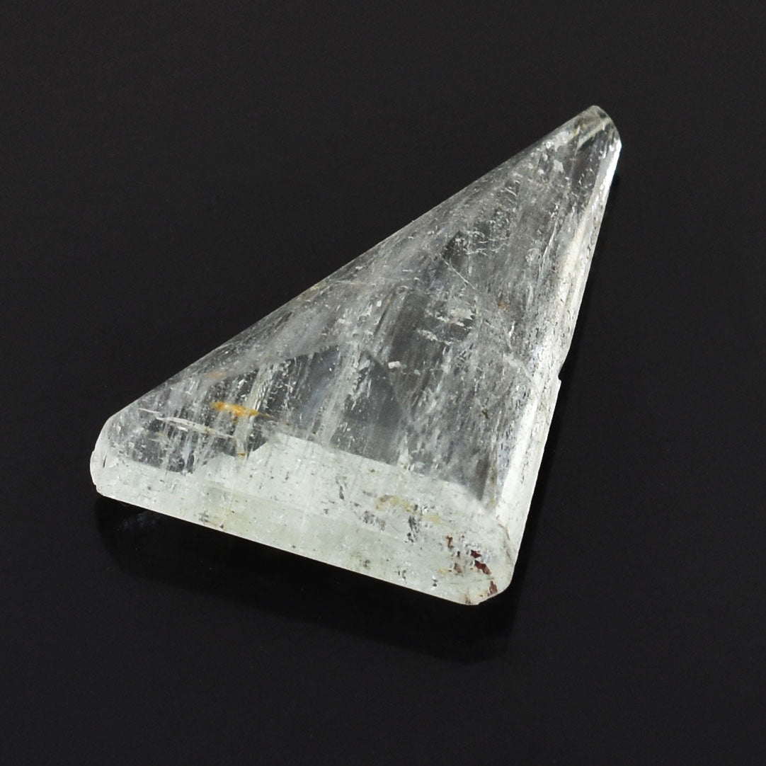 Triangular piece of clear, crystalline mineral or gemstone with a translucent appearance.