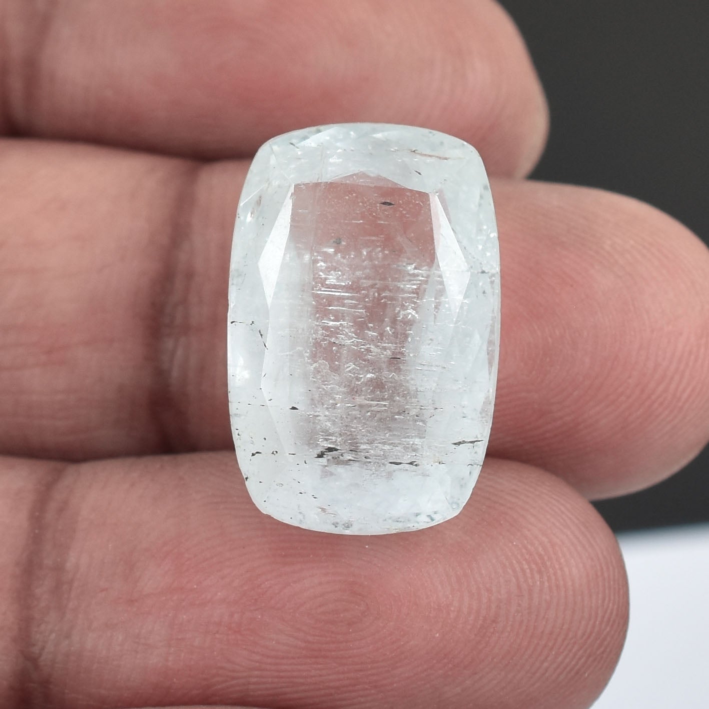 Clear, rectangular-cut gemstone or crystal held between fingers.