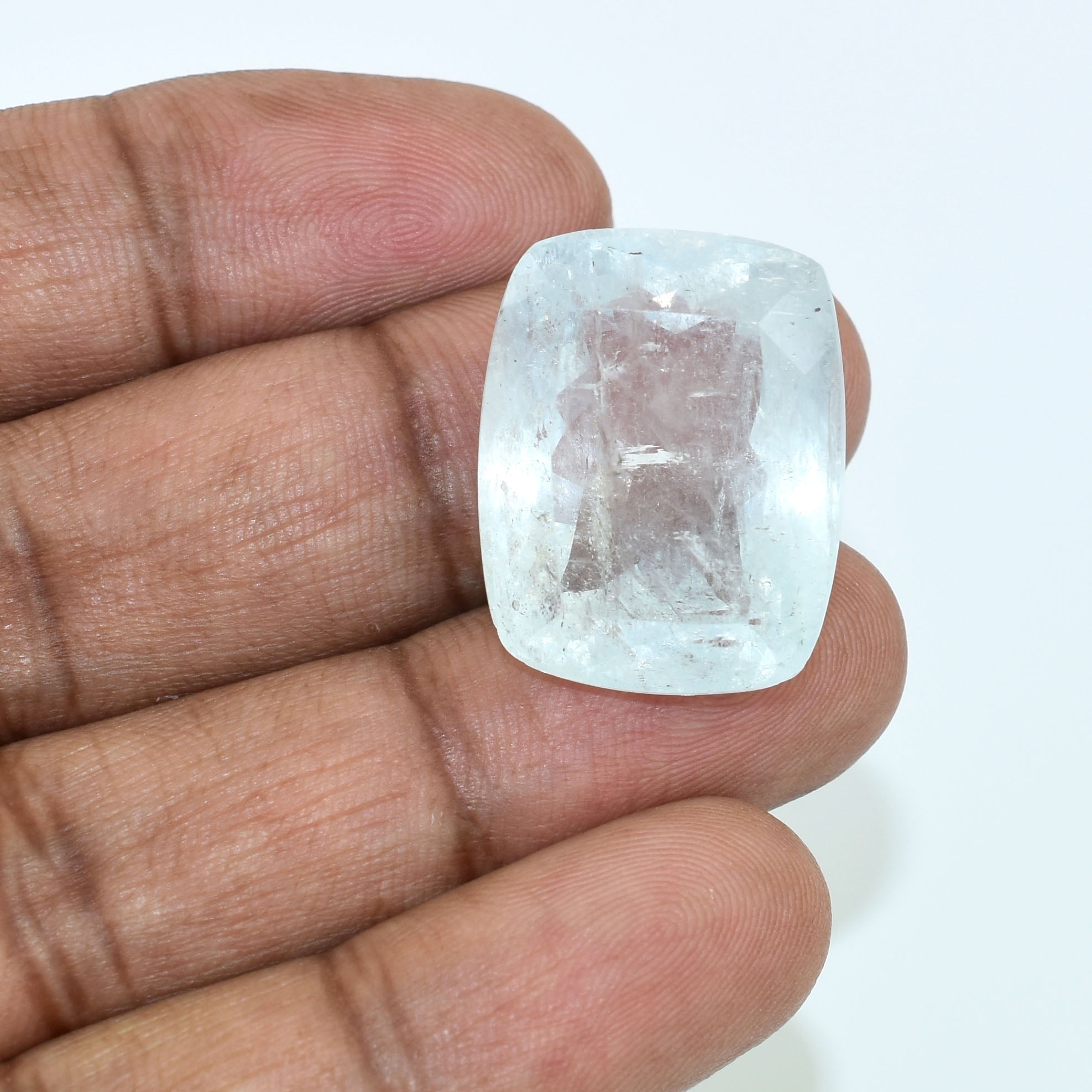 Rectangular, translucent gemstone or crystal held between fingers.