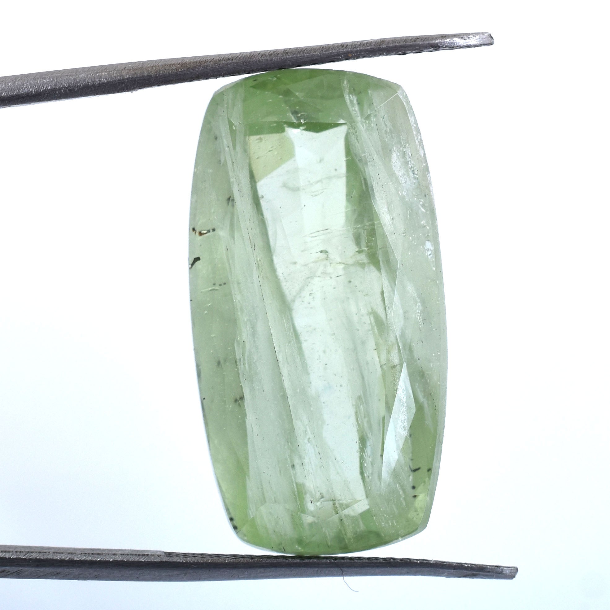 Pale green, elongated gemstone held by tweezers.