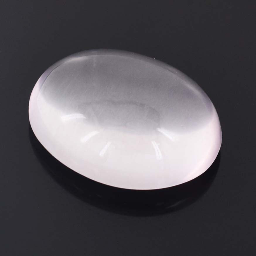 Smooth, oval-shaped white gemstone or cabochon against a dark background.