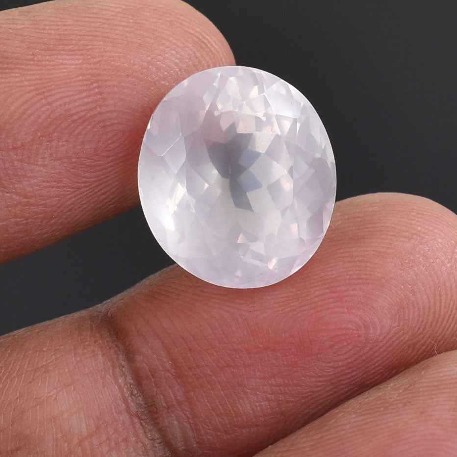 Translucent oval gemstone held between two fingers.