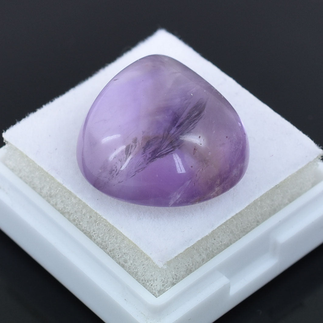 Polished purple gemstone with a smooth, rounded surface.