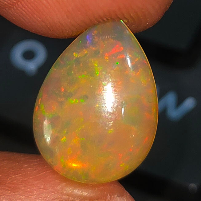 Teardrop-shaped opal gemstone displaying vibrant, multicolored fire.