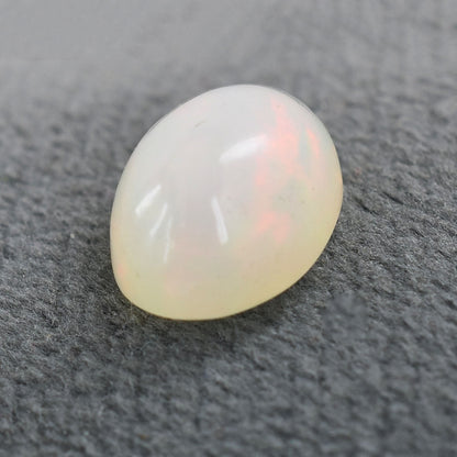 Oval-shaped opal gemstone with a milky white appearance and subtle iridescent hues.