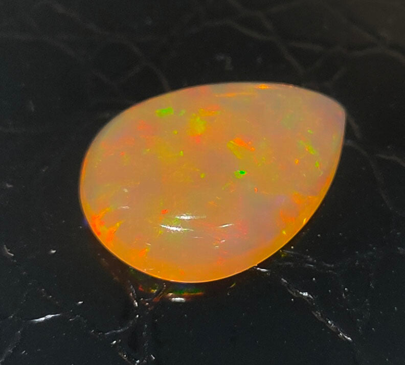 Teardrop-shaped opal gemstone with vibrant orange and yellow fire.