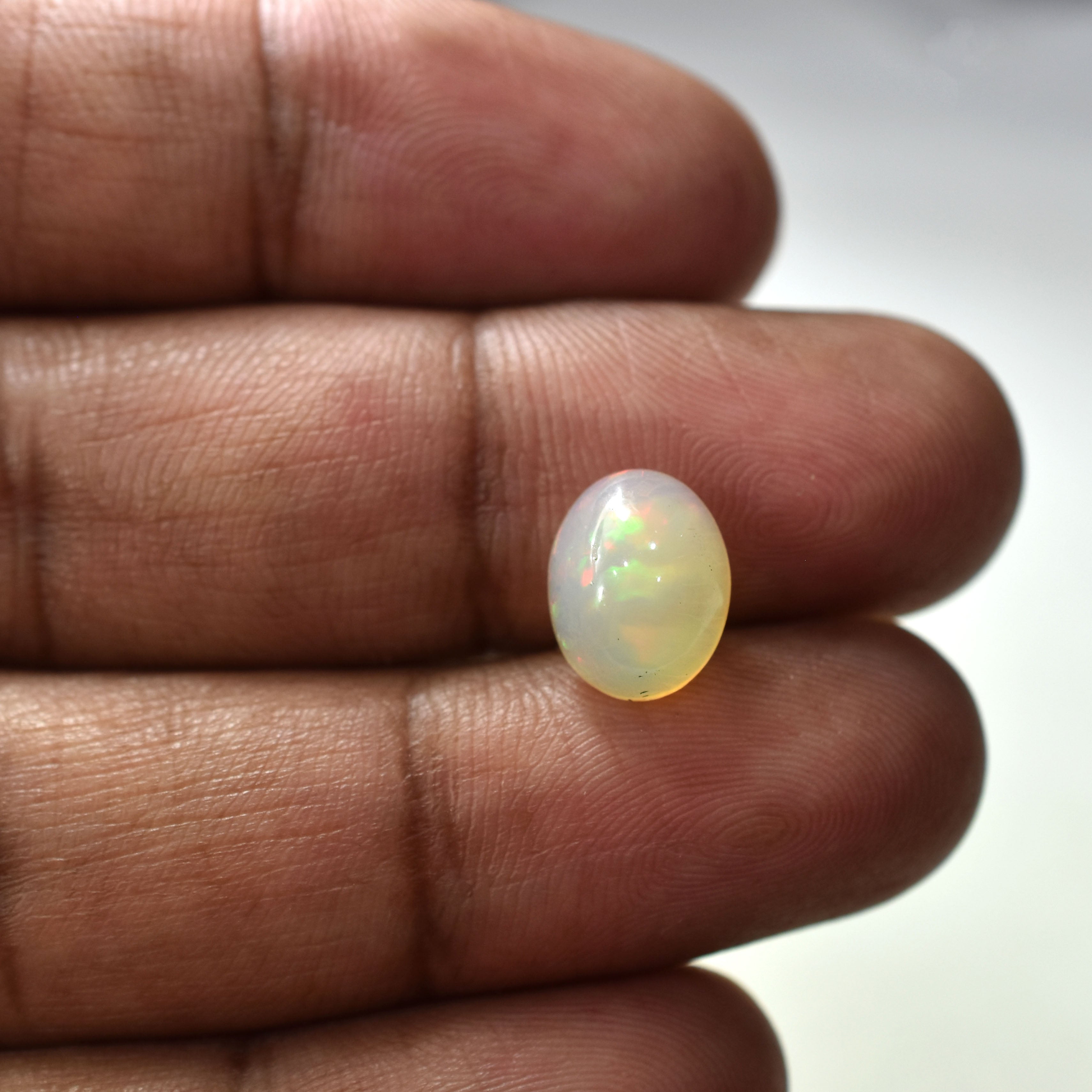 Oval-shaped opal gemstone with a milky white color and iridescent sheen.