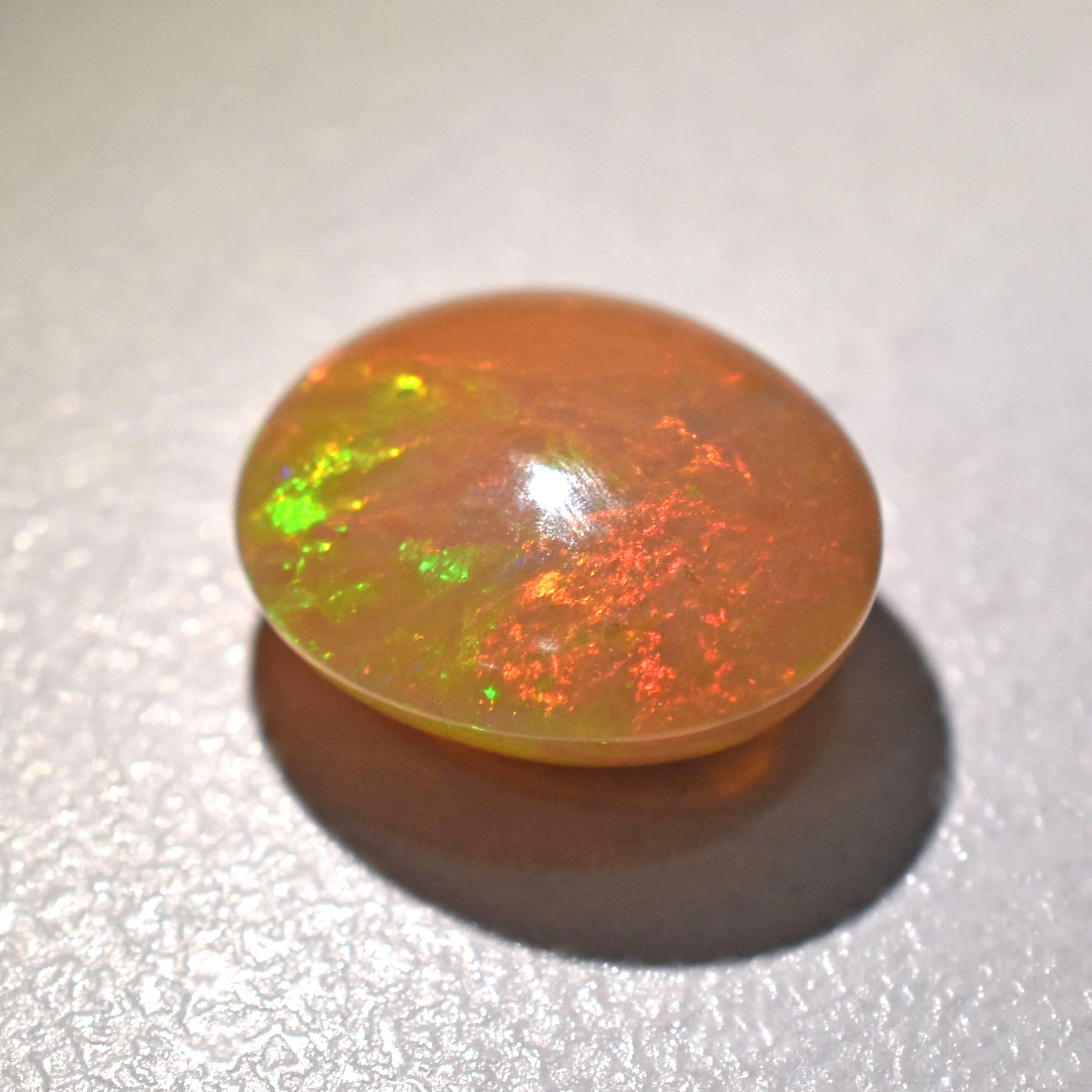 Opal gemstone with vibrant green and red flashes of color.