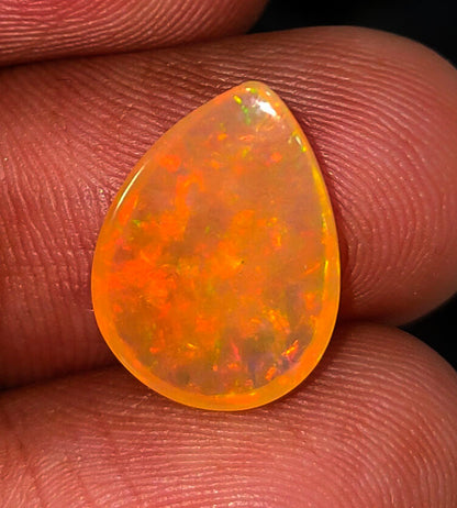 Teardrop-shaped opal gemstone with vibrant orange and yellow fire patterns.