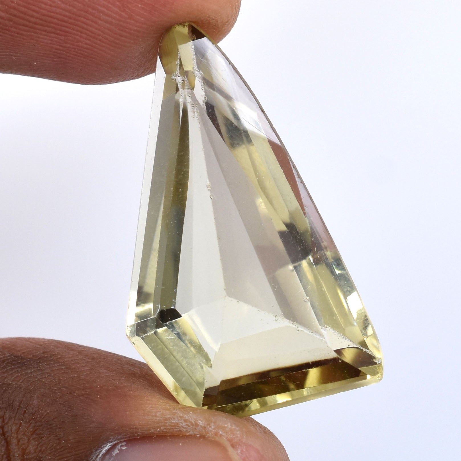 Triangular-cut gemstone or crystal held between two fingers.