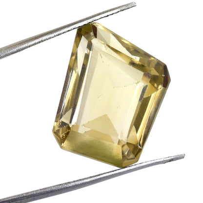 Emerald-cut yellow gemstone held by tweezers.