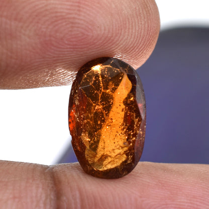 Amber-colored gemstone or polished stone held between two fingers.