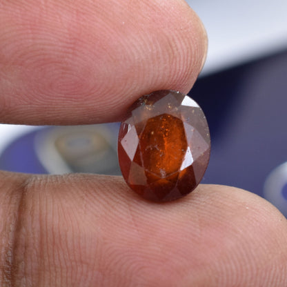 Faceted amber-colored gemstone held between two fingers.