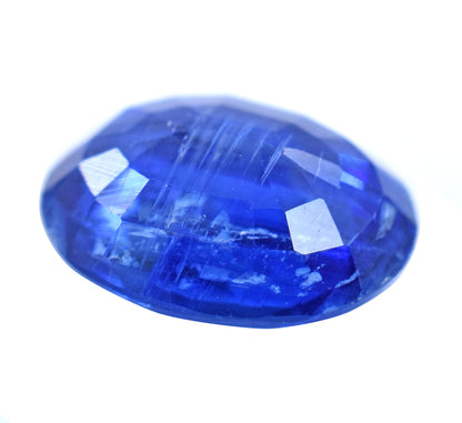 Vibrant blue oval-cut gemstone with facets reflecting light.