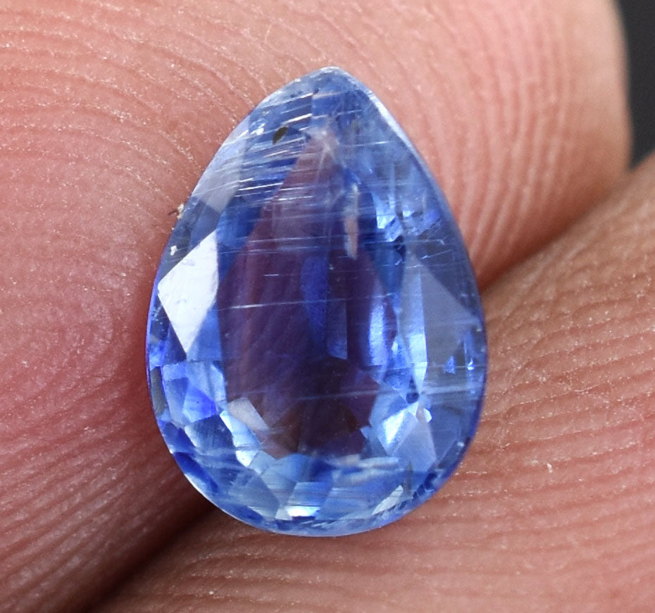 Teardrop-shaped blue gemstone with facets reflecting light.