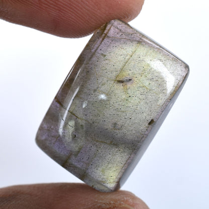 Translucent gemstone or crystal with visible inclusions held between fingers.