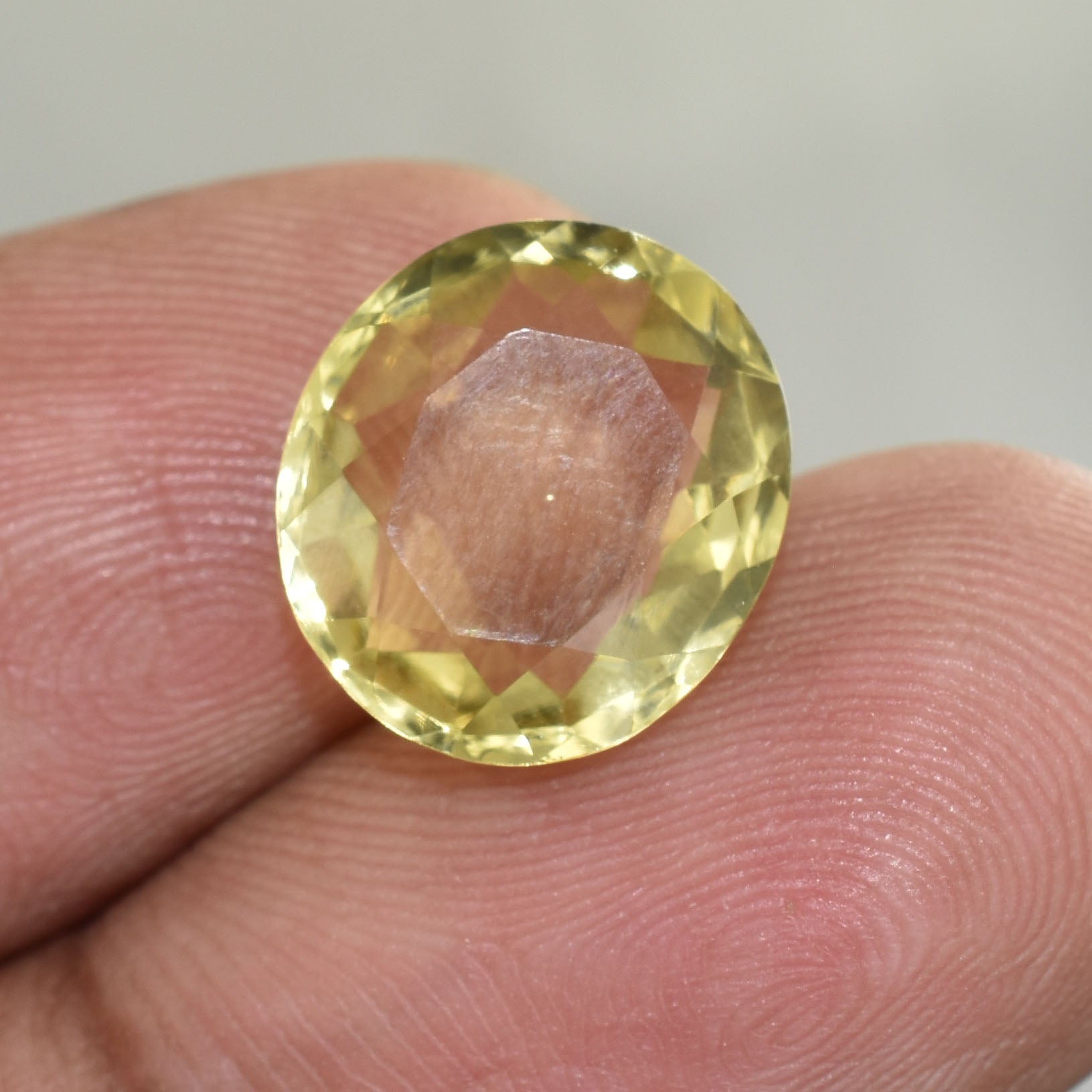 Faceted yellow gemstone held between fingertips.