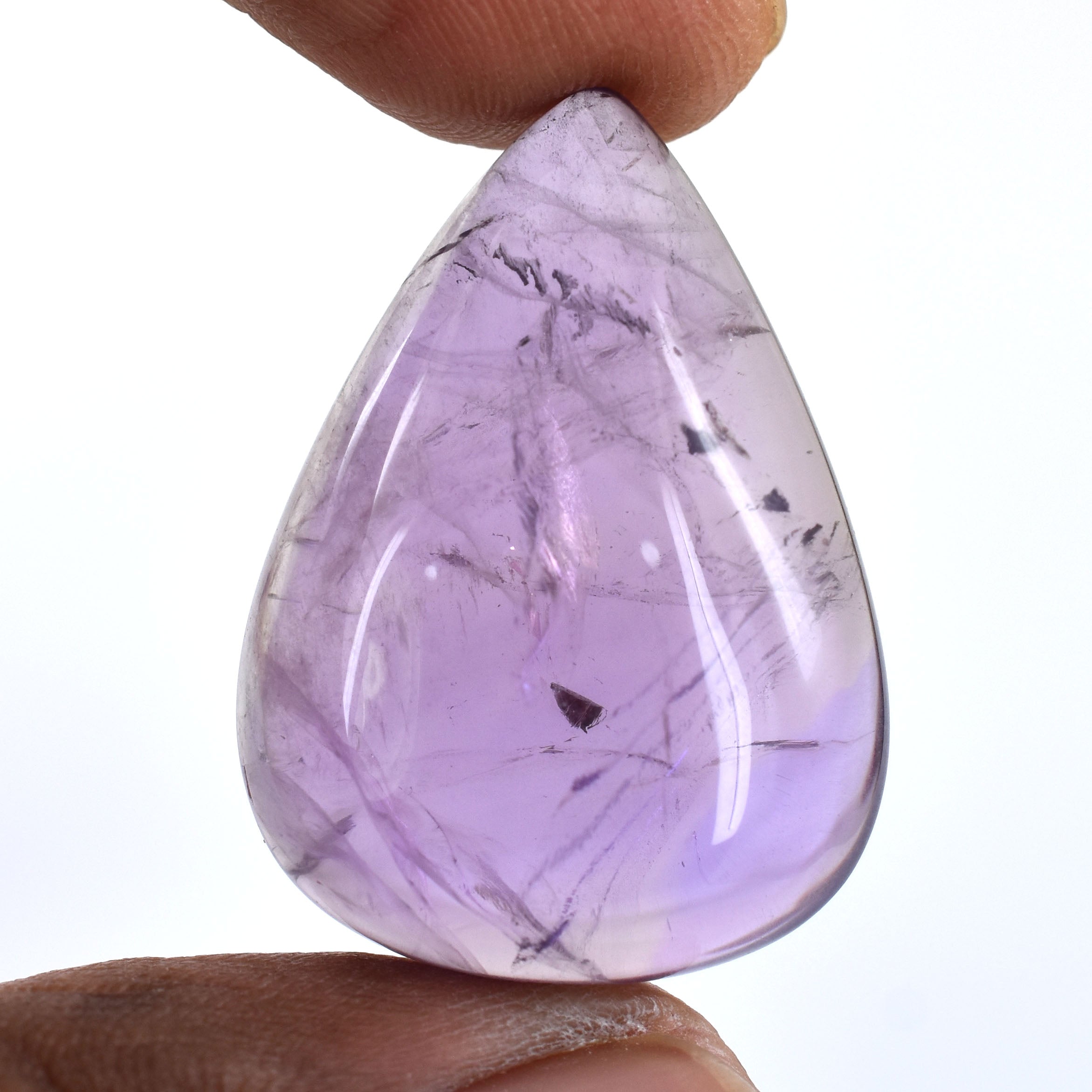 Teardrop-shaped purple gemstone with internal inclusions held between fingers.