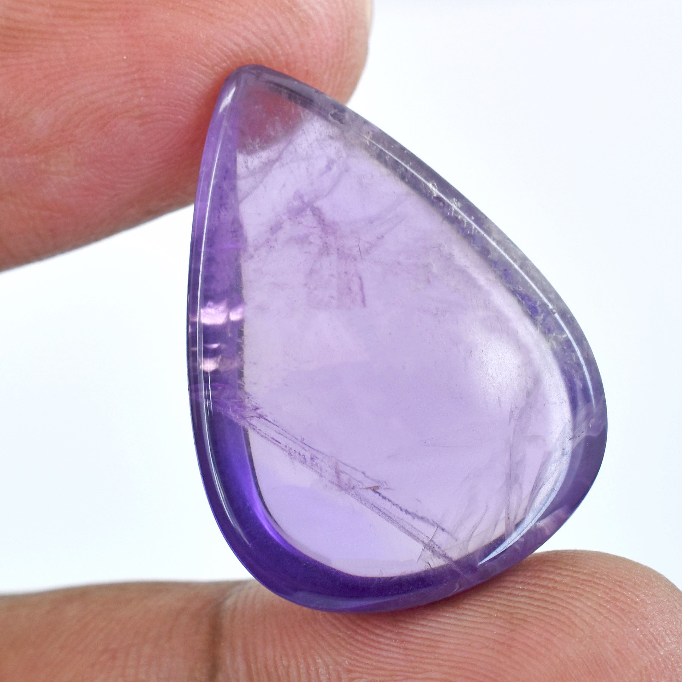 Teardrop-shaped purple gemstone held between fingers.