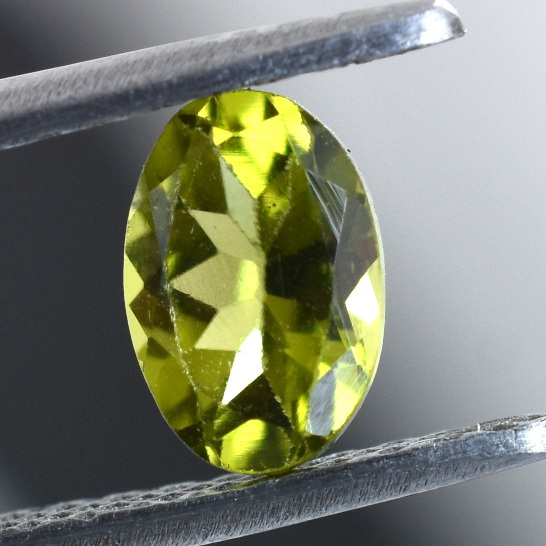 Faceted oval-shaped gemstone with a vibrant yellow-green color.