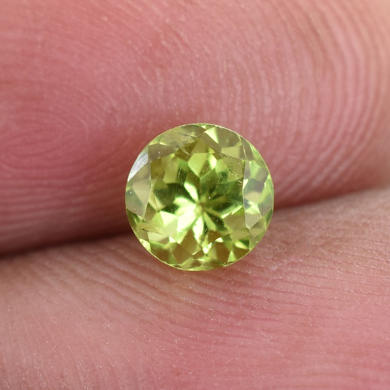 Round-cut, light green gemstone with facets reflecting light.