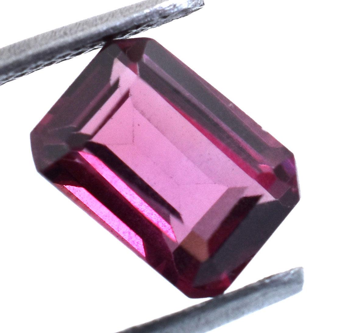 Emerald-cut pink gemstone held by tweezers.