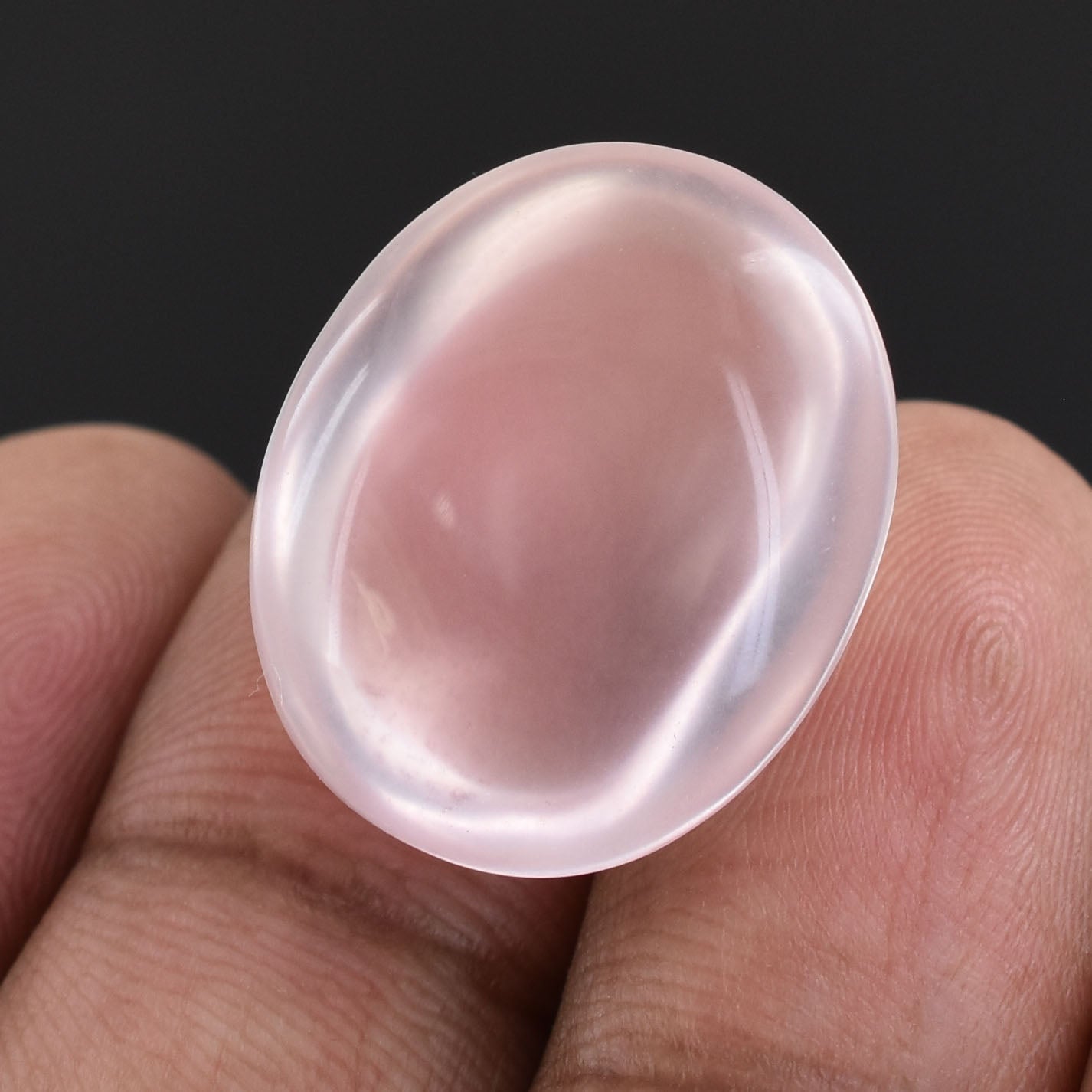 Translucent oval gemstone or crystal held between fingers.