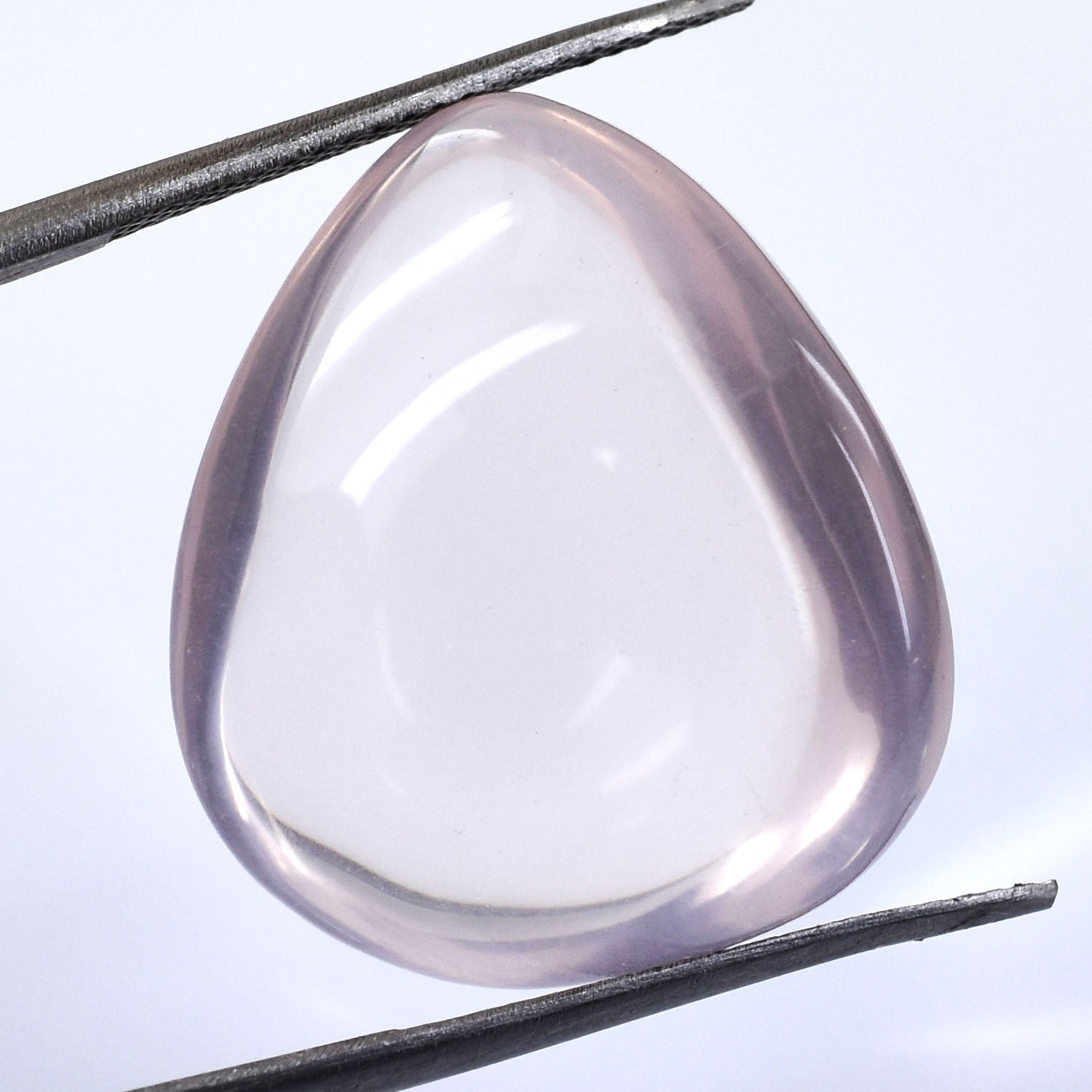 Smooth, translucent rose quartz gemstone held between tweezers.