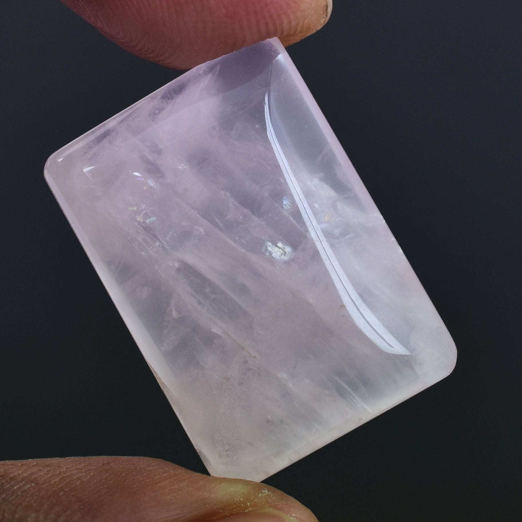 Translucent rectangular ice cube held between two fingers.