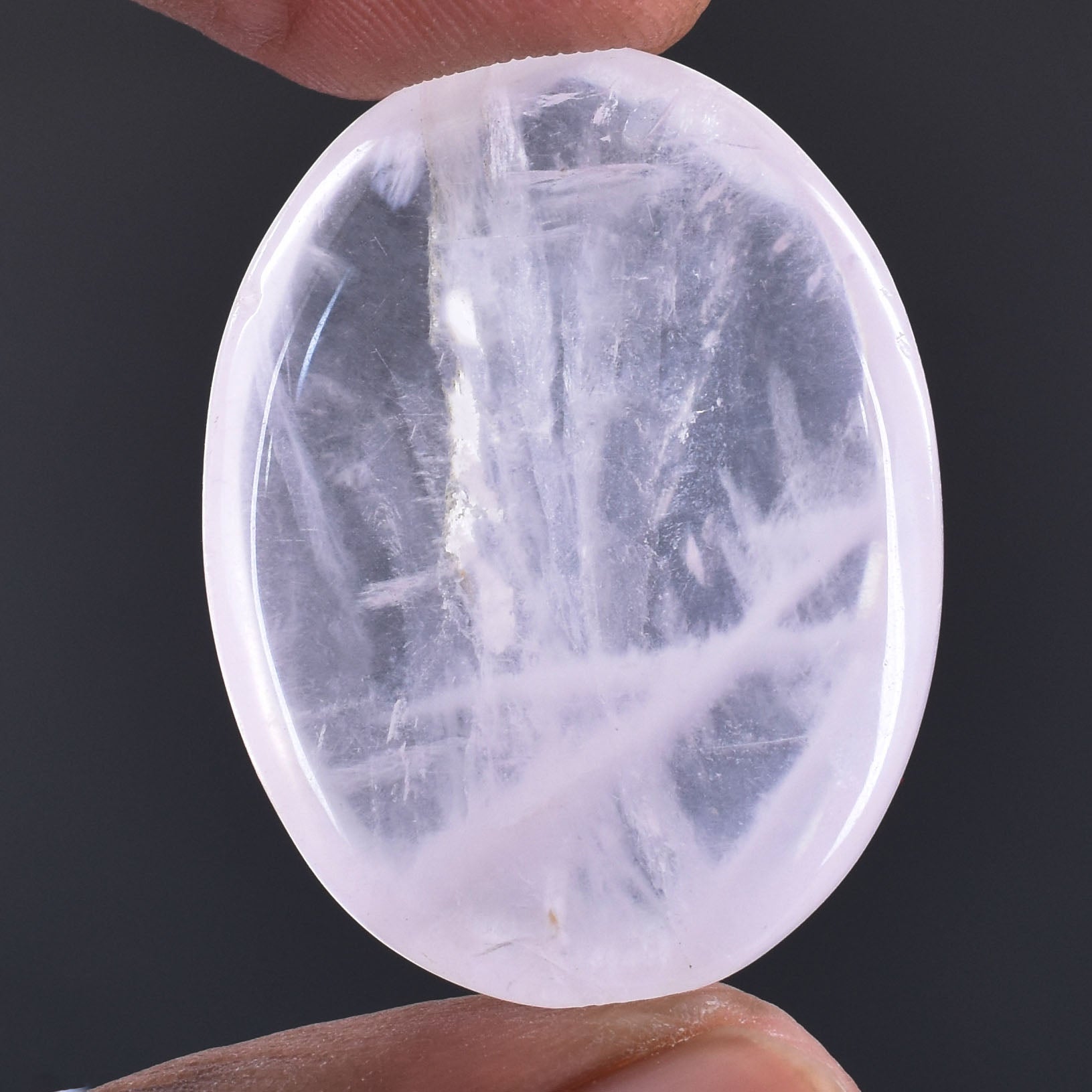 Oval-shaped, translucent gemstone or crystal with internal striations.