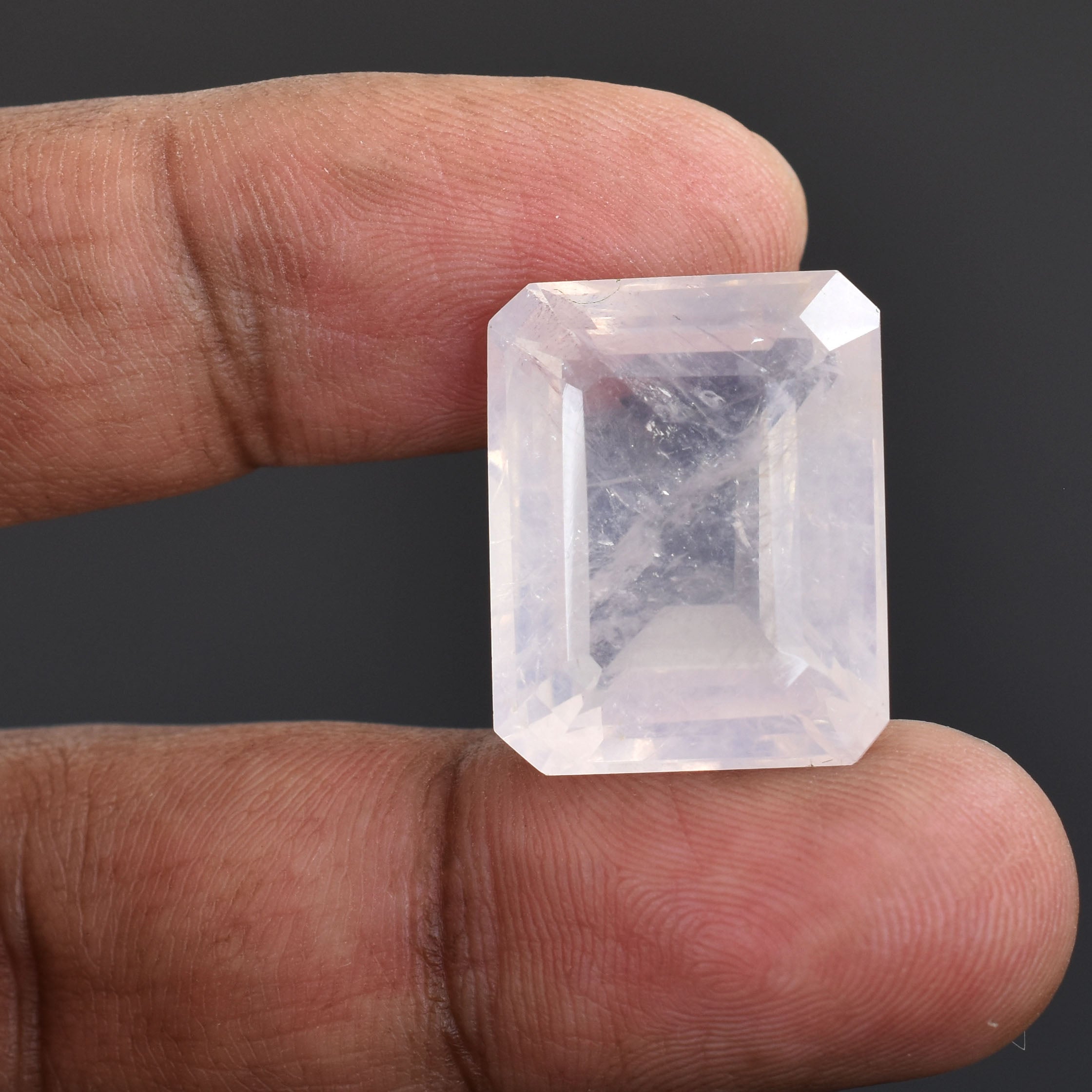 Rectangular-cut, translucent gemstone held between two fingers.