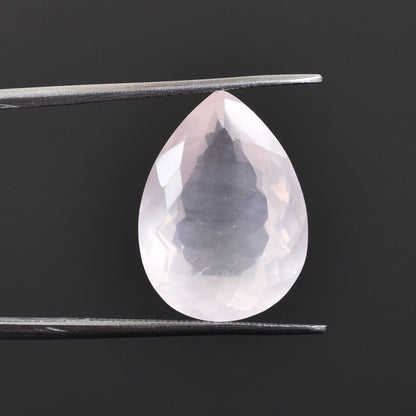 Pear-shaped, translucent gemstone held by tweezers.