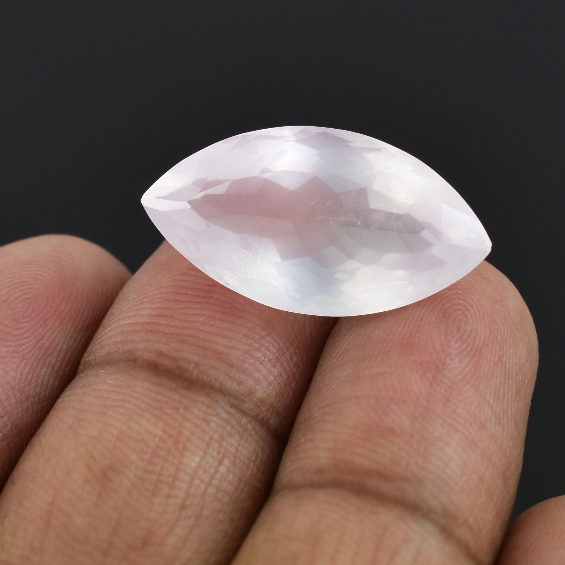 Marquise-cut gemstone or crystal held between two fingers.