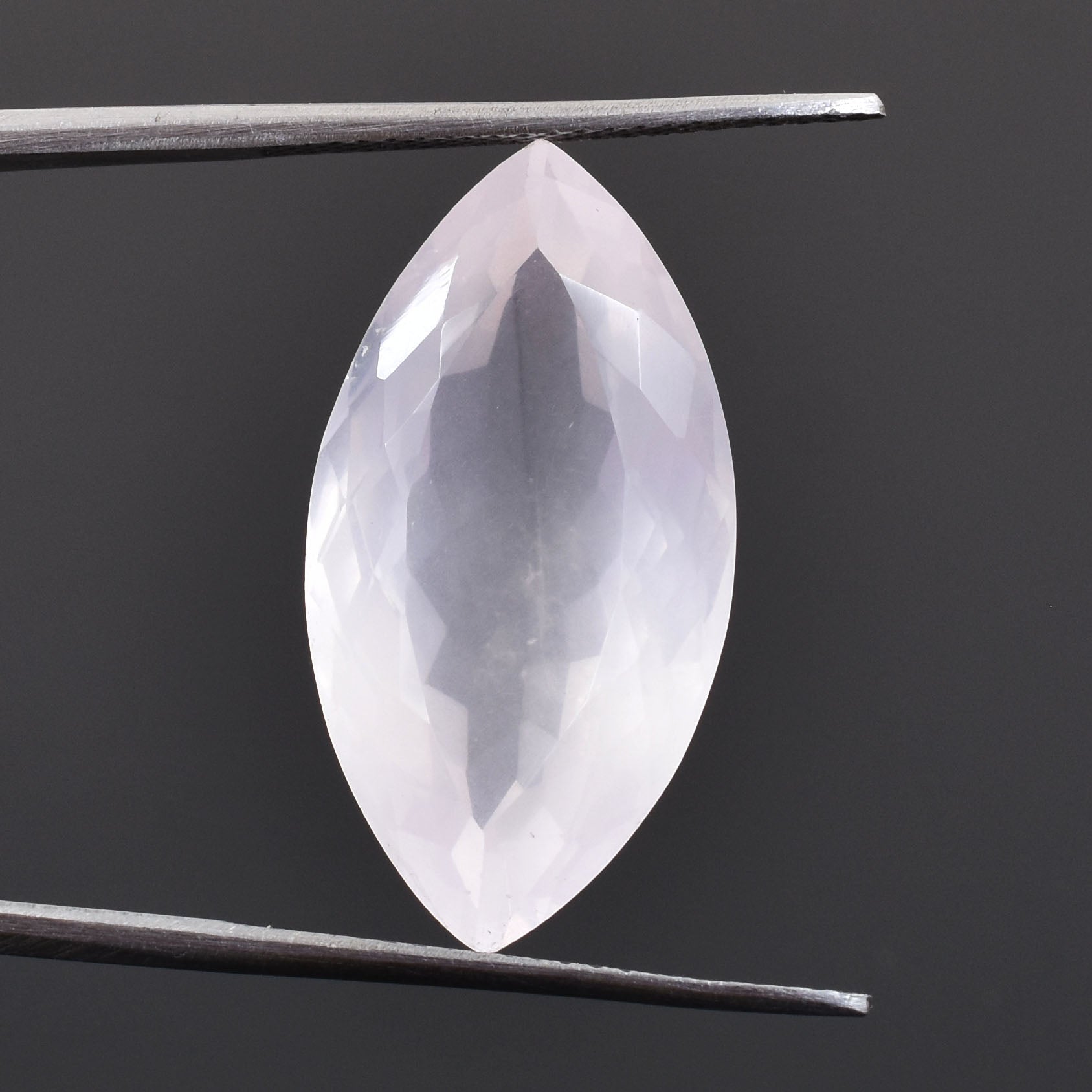 Marquise-cut gemstone held between tweezers.