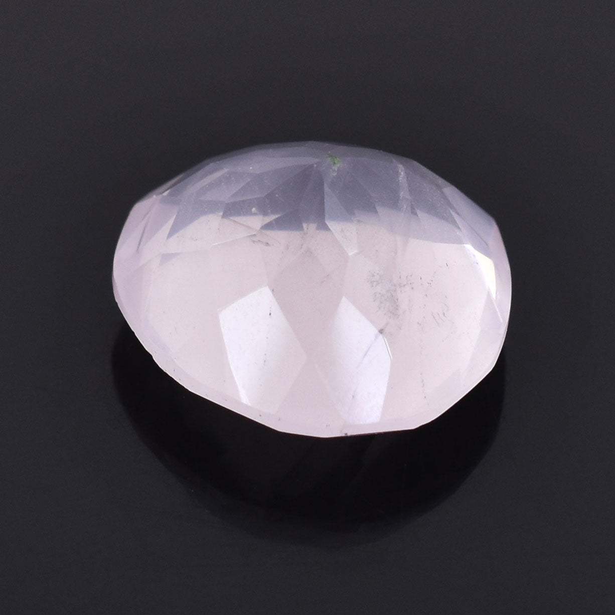 Smooth, pale pink gemstone or crystal with a rounded, cabochon-like shape.