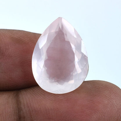 Teardrop-shaped, faceted, translucent gemstone held between fingers.