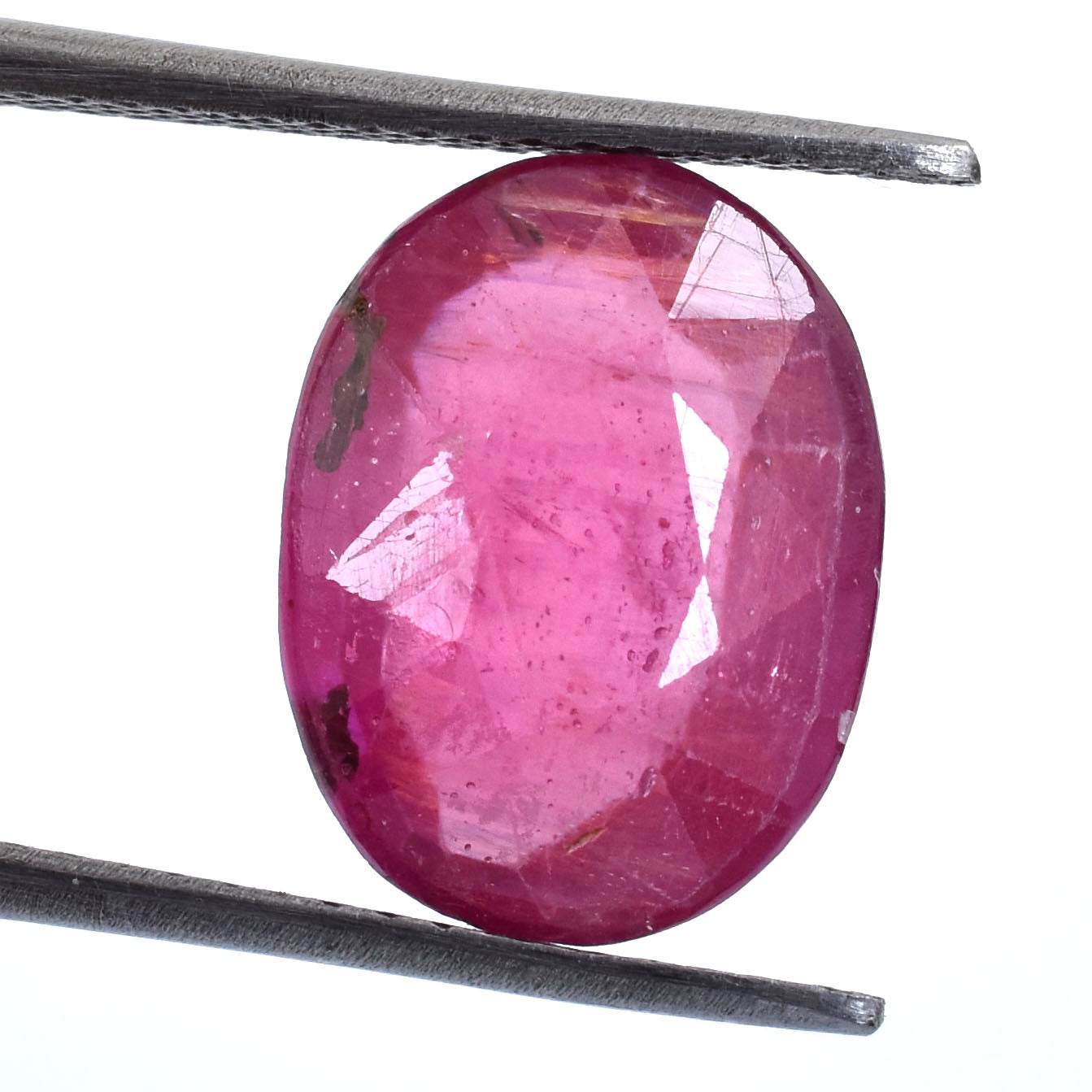 Oval-shaped pink gemstone with facets, likely a ruby or pink sapphire.