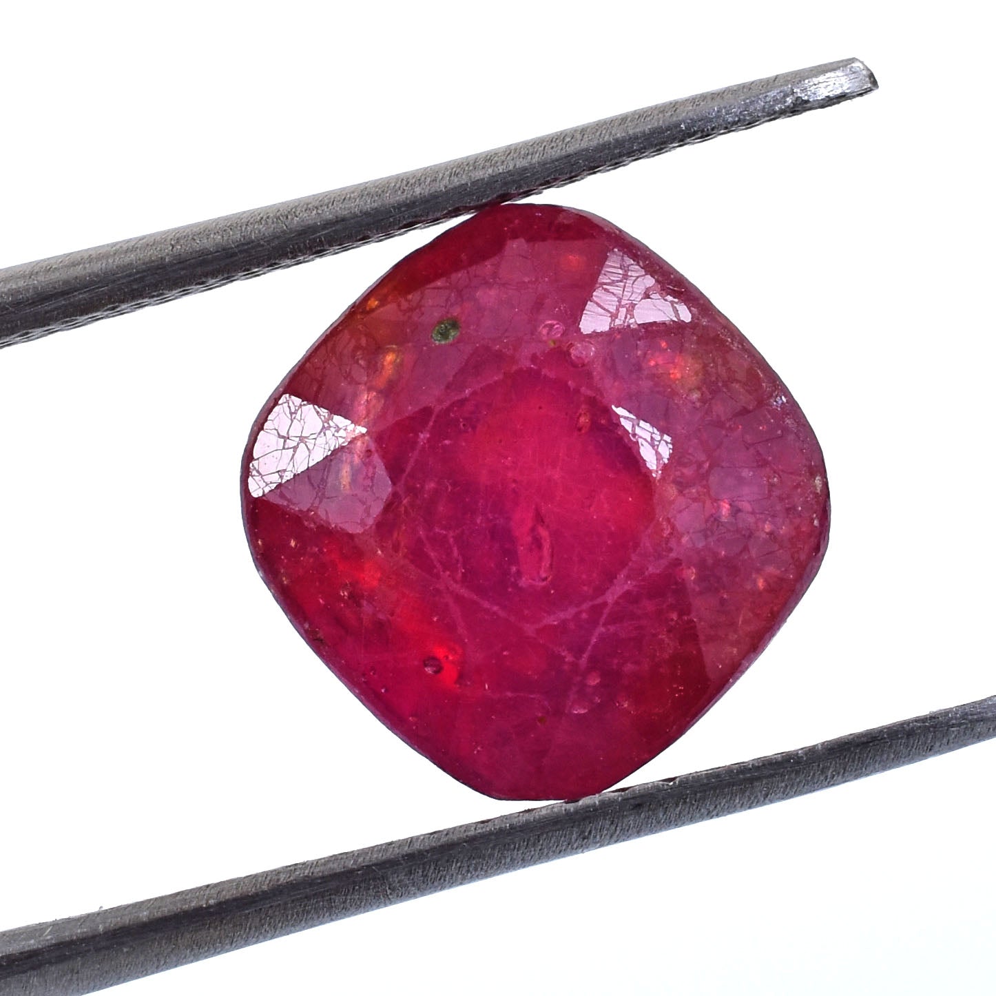 Cushion-cut ruby gemstone held by tweezers.