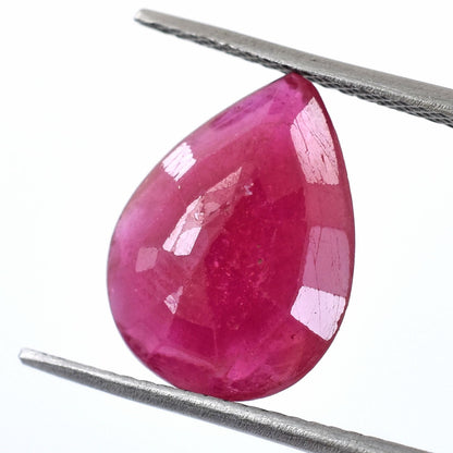 Pear-shaped pink gemstone held by tweezers.