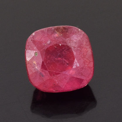 Cushion-cut pink gemstone with visible facets and inclusions.