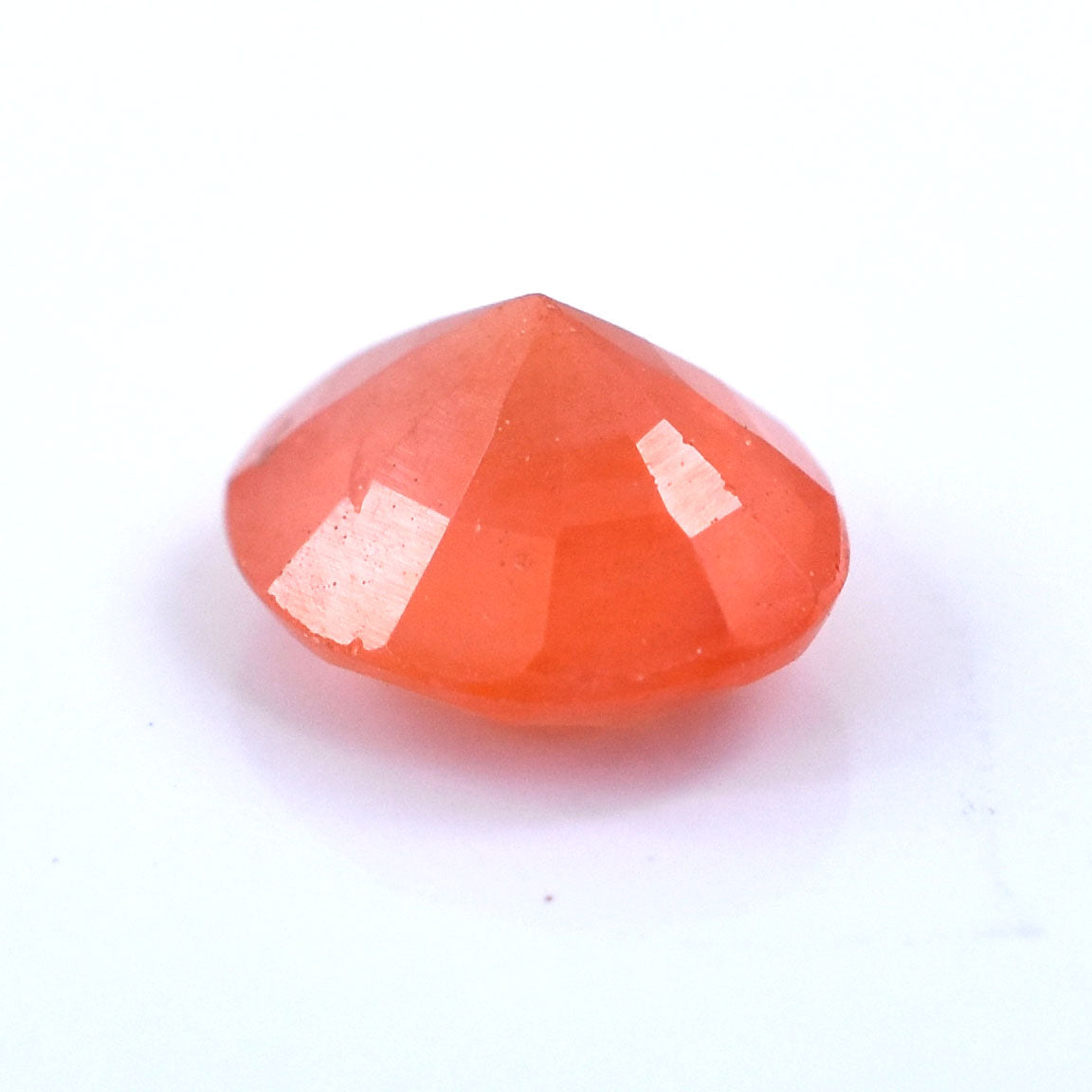 Faceted orange gemstone or crystal with a rounded shape.